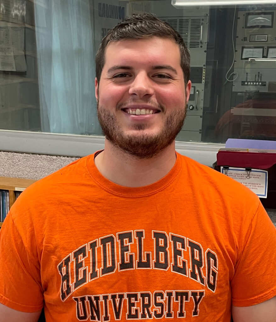 Max smiling and wearing an orange color shirt